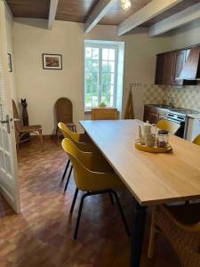 eine Küche mit einem Holztisch und gelben Stühlen in der Unterkunft Gîte du Dolmen in Guiscriff