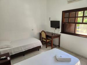 a room with two beds and a desk with a computer at Hotel Colonial in Cajati