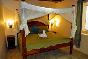 una camera con letto a baldacchino e cigno di The Still Beach Resort-Room 5 a Soufriere