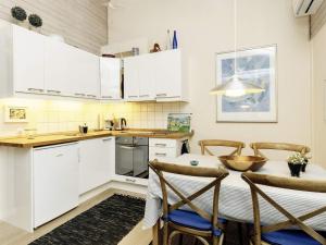 a kitchen with white cabinets and a table and chairs at Holiday home Ærøskøbing XI in Ærøskøbing