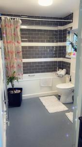 a bathroom with a tub and a toilet and a sink at Stay in Woking with Chidi in Horsell