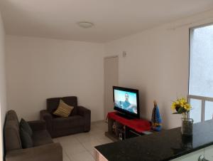 a living room with a couch and a television at Apartamento Padrão 2° Andar in Vespasiano