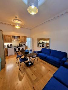 a living room with a blue couch and a table at Lovely Ground Floor Home with Private Garden by Earls Court Station in London