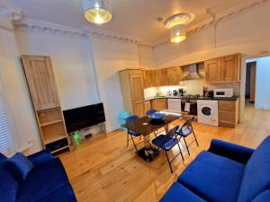 a living room with a table and chairs and a kitchen at Lovely Ground Floor Home with Private Garden by Earls Court Station in London