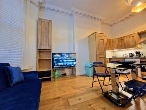 a living room with a couch and a table and a tv at Lovely Ground Floor Home with Private Garden by Earls Court Station in London