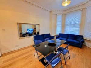 a living room with a table and a blue couch at Lovely Ground Floor Home with Private Garden by Earls Court Station in London