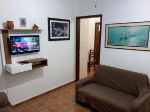a living room with a couch and a flat screen tv at Apartamentos Petrópolis in Ubatuba