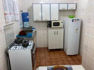 a small kitchen with a stove and a microwave at Apartamentos Petrópolis in Ubatuba