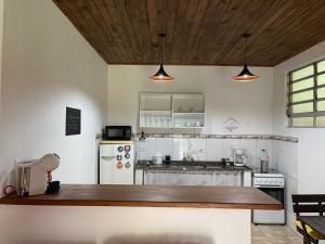 a kitchen with a counter and a white refrigerator at Chalé Rio das Pedras in Santo Antônio do Pinhal