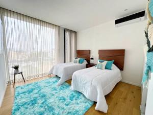 グアダラハラにあるHomely Escape in Providencia.の大きな窓付きの客室で、ベッド2台が備わります。