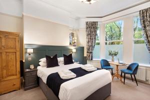 a bedroom with a large bed and a table and chairs at Fountains Guest House - Harrogate Stays in Harrogate