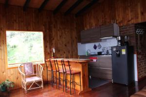 uma cozinha com um balcão, um frigorífico e uma mesa em cabañas Arcoíris del lago Nº 2 em Pasto