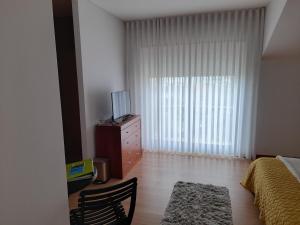 a bedroom with a bed and a dresser with a television at Azoresaccommodation in Lagoa