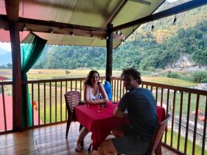 a man and a woman sitting at a table on a balcony at Tran Xuan Homestay in Ba Be18