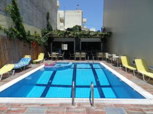 a large swimming pool with chairs and a table at Haris Apartments in Hersonissos
