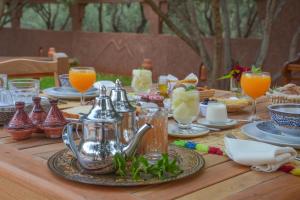 a wooden table with a tea kettle and glasses of orange juice at Dar Arraha Ouirgane in Ouirgane