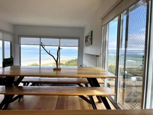 a dining room with a table and a large window at Three Little Birds at Freycinet in Coles Bay
