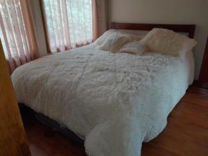 een bed met witte lakens en kussens in een slaapkamer bij cabañas Arcoíris del lago Nº 5 in Pasto