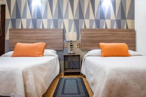 2 camas con almohadas de color naranja en una habitación en Hotel Estefania, en Morelia