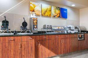 a kitchen with wooden cabinets and a counter at Comfort Inn and Suites Van Buren - Fort Smith in Van Buren