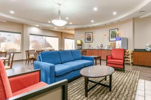 a living room with a blue couch and red chairs at Comfort Inn & Suites Van Buren - Fort Smith in Van Buren