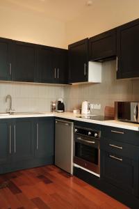 cocina con armarios negros y horno con fogones en Antrim Road Apartments Belfast, en Belfast