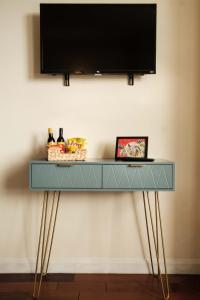 TV de pantalla plana y consola azul con patas doradas. en Antrim Road Apartments Belfast, en Belfast