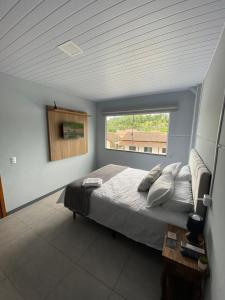 a bedroom with a large bed with a window at Morada Pomerode 2 in Pomerode