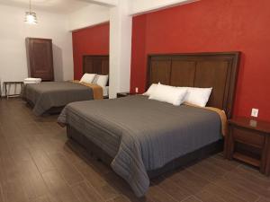 ein Hotelzimmer mit 2 Betten und roten Wänden in der Unterkunft Hotel Cantera Jaguar in San Juan Teotihuacán
