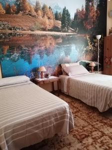 two beds in a room with a painting of a lake at B&b Fabra Casa Mia e non solo in Falvaterra