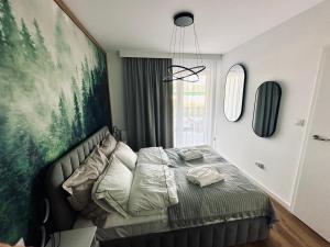 ein Schlafzimmer mit einem Bett mit einem großen Gemälde an der Wand in der Unterkunft Mountain Shine - Apartment, SPA and Parking in Zakopane