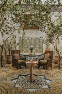 eine Terrasse mit einem Tisch, Stühlen und Bäumen in der Unterkunft Riad Samsara in Marrakesch