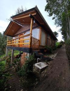 eine kleine Holzhütte mit einer Veranda und einem Waschbecken in der Unterkunft cabañas Arcoíris del lago Nº 5 in Pasto