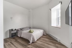 a white bedroom with a bed and a window at Spacious 2 bedroom apartment - 02 in Montreal
