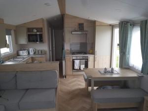 濱海克拉克頓的住宿－8 Birth Mobile Luxury home C016 8SG St Osyth near Clacton on Sea，厨房以及带沙发和桌子的客厅。