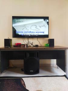 a computer desk with a television on a wall at Wildan Homestay in Mangun