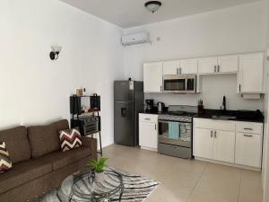 ein Wohnzimmer mit einem Sofa und einer Küche in der Unterkunft ElDorado Guesthouse in Roseau