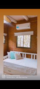 1 dormitorio con 1 cama blanca grande y ventana en Casitas De Montaña en Traslasierra 2 en Los Hornillos