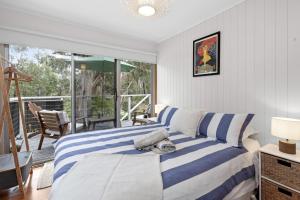 une chambre avec un lit à rayures bleues et blanches dans l'établissement Barca View Cottage, à Apollo Bay