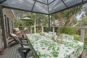 une table avec des assiettes vertes sur une terrasse dans l'établissement Barca View Cottage, à Apollo Bay