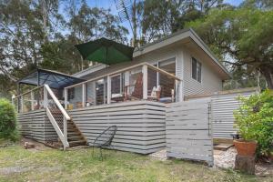 une maison avec un parasol vert au-dessus dans l'établissement Barca View Cottage, à Apollo Bay