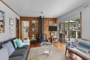 un salon avec un canapé et une cheminée dans l'établissement Barca View Cottage, à Apollo Bay