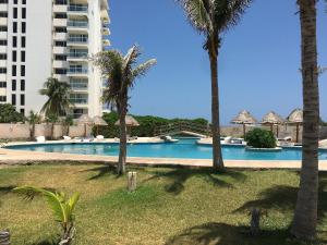 a swimming pool with palm trees and a building at Beautiful Beach Front Pent House in Cancun!!! in Cancún