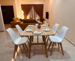 una mesa de madera con sillas blancas en la sala de estar. en Kluang 4 bedrooms 4 bathrooms, en Keluang