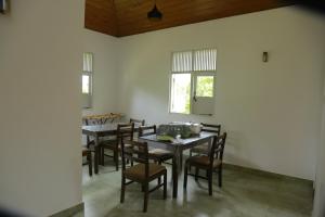 a dining room with tables and chairs and windows at Serenity Villa Anuradhapura in Anuradhapura