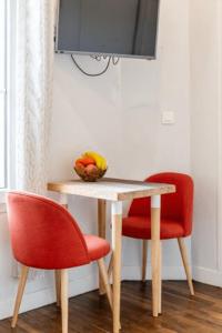 een tafel met twee rode stoelen en een fruitschaal bij Charmant & Cosy 2 pièces La Defense-Champs Elysees in Puteaux