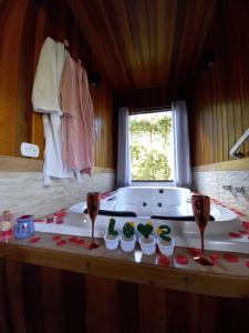 eine Badewanne mit zwei Weingläsern und einer Badewanne in der Unterkunft Chalé Riacho Frio in Gonçalves