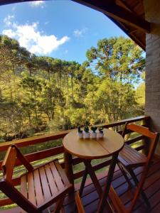 una mesa y sillas en una terraza con vistas a los árboles en Chalé Riacho Frio, en Gonçalves