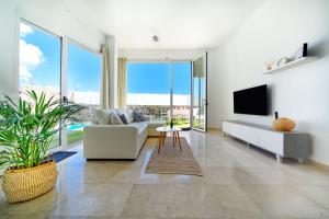 sala de estar con sofá blanco y TV en Villa Cacemar Salobre, en Las Palmas de Gran Canaria