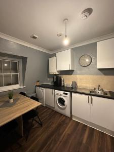 a kitchen with white cabinets and a table and a sink at 1 bedroom in kingscross, St Pancras, London in London